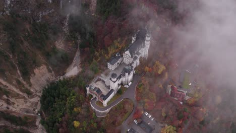 Castillo-De-Neuschwanstein-Con-árboles-Coloridos-Durante-La-Temporada-De-Otoño-En-Un-Día-Nublado,-Antena