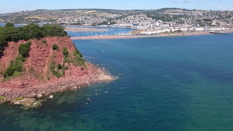 aerial orbiting shot of ness cove cliffs and babbacombe bay during sunny day with blue sky in shaldon,england