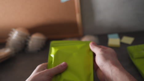 pov hand-sealing green bag for marketplace sales, placing on table, next bag ready