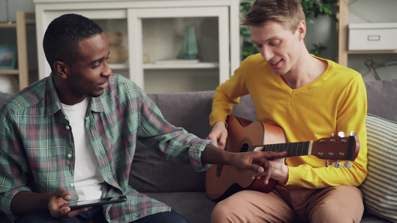 Two friends learning guitar at home