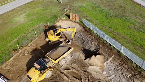 aerial view of an excavator loading soil into a dump truck at a construction site in cromwell, new zealand