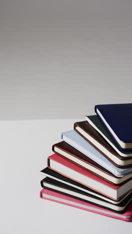 vertical video of stack of books with copy space on grey background, in slow motion