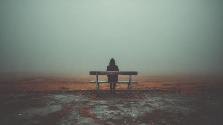 A solitary figure sits on a bench, enveloped by a thick fog that creates an ethereal atmosphere, blending the boundaries between reality and dreams