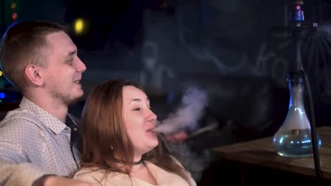 una pareja disfrutando de un narguile en un café por la noche
