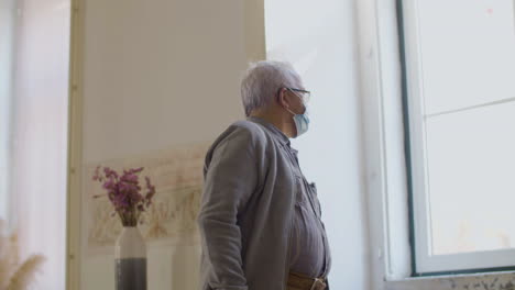 medium shot of mature man in medical mask looking at his watch