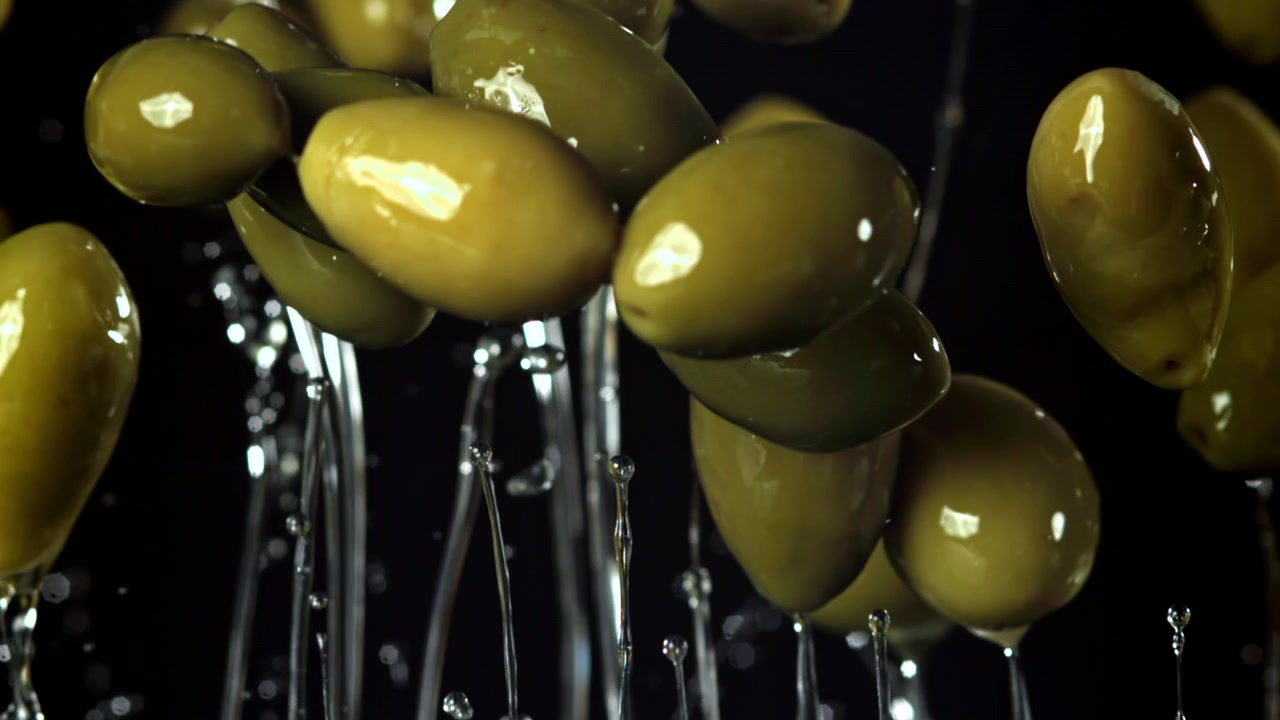 Olive verdi fresche in caduta al rallentatore con schizzi d'acqua