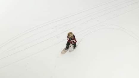 hombre adulto con un gran sombrero de piel, camina y juega con raquetas de nieve tradicionales en un lago congelado con sus perros en el norte de canadá