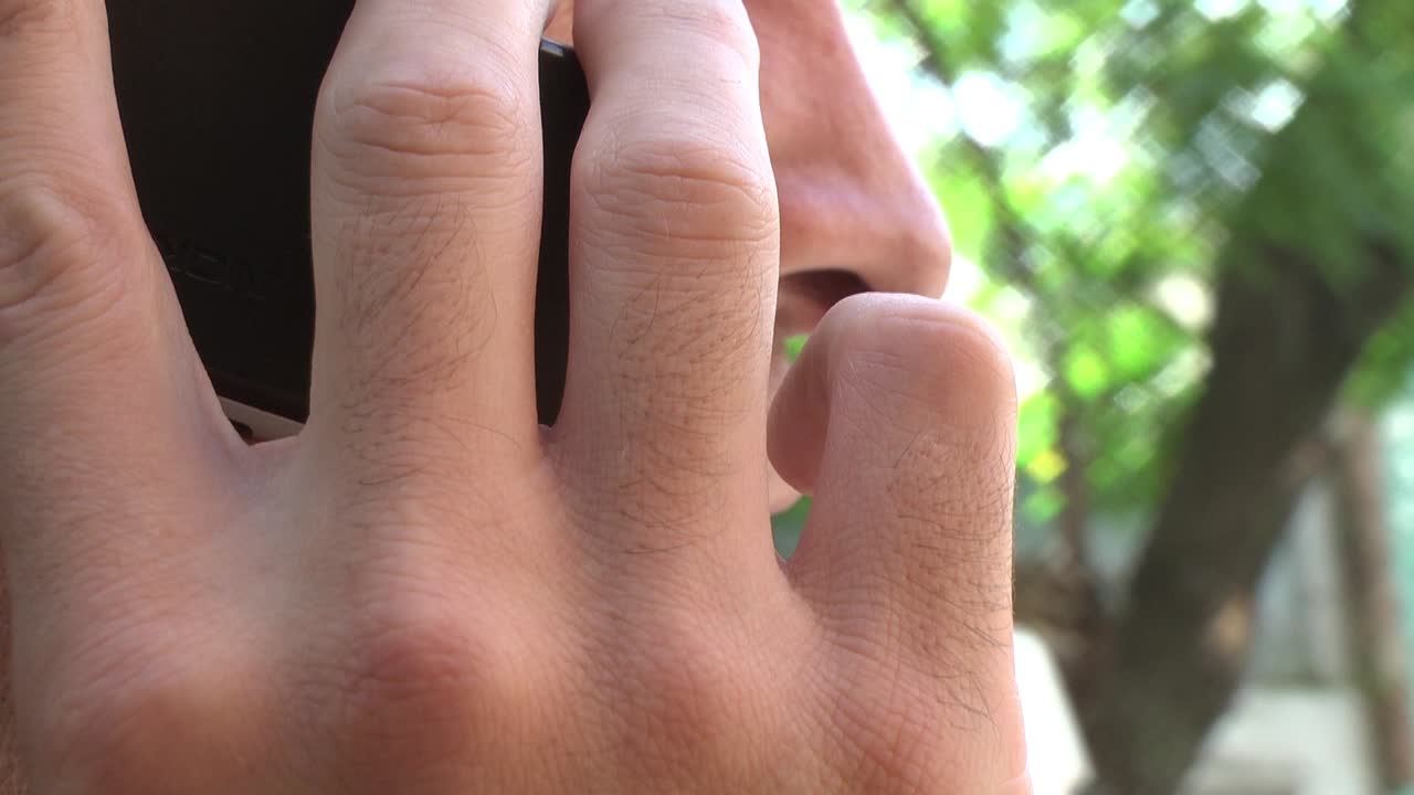 Primo piano di un uomo che parla al cellulare all'aperto