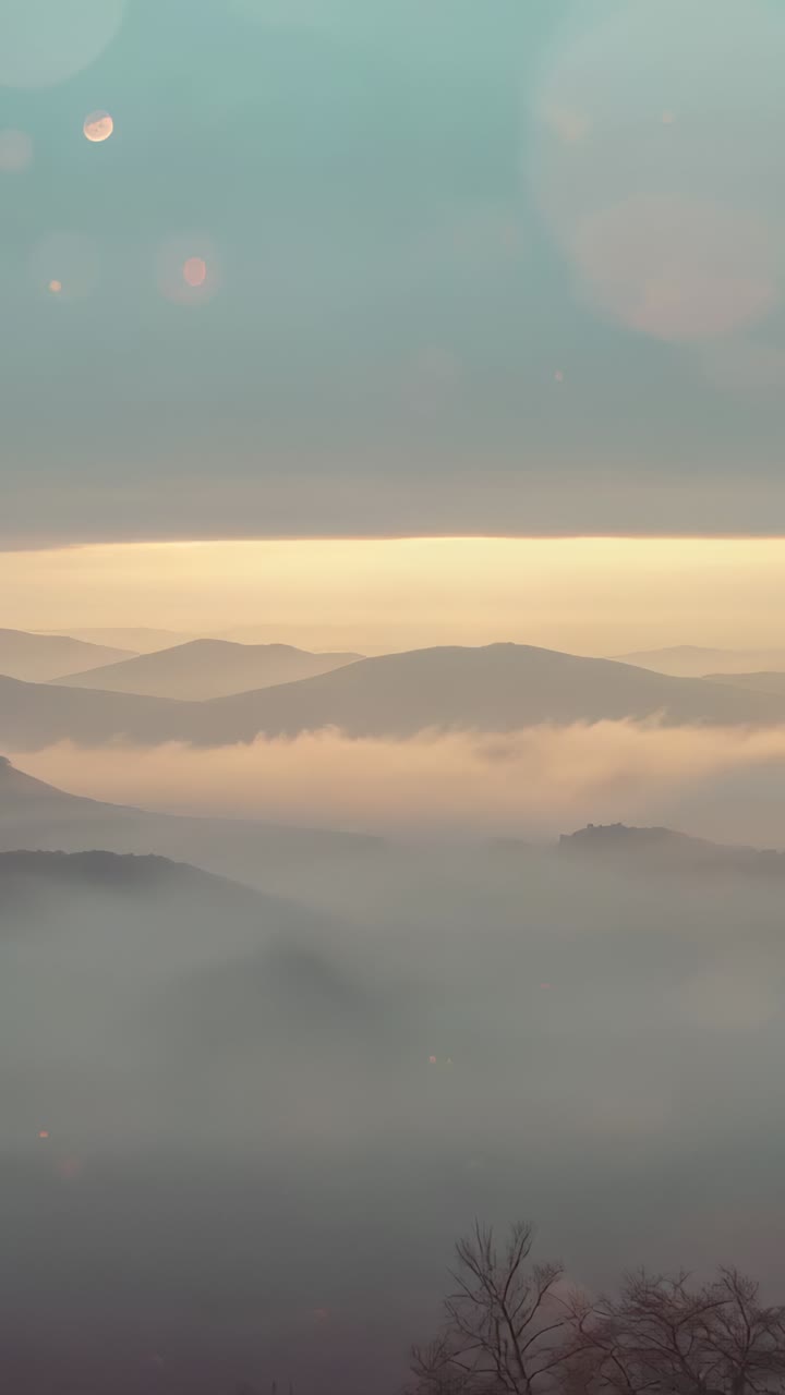 Vertical video: Watching fog drifting in valley from peak with sunrise arriving, revealing ridges