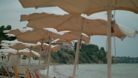 windy weather on the sea shore. empty beach and shaking sun umbrellas, greece