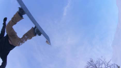 Super-slow-motion-backflip-on-a-snowboard-over-camera,-waving-and-smiling