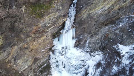 aerial view of a frozen waterfall with a person standing in front of it