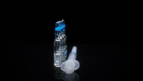 close-up of syringe and ampoules with vaccine against coronavirus. showing sample of medicine on black background, vaccination against covid-19, laboratory research concept