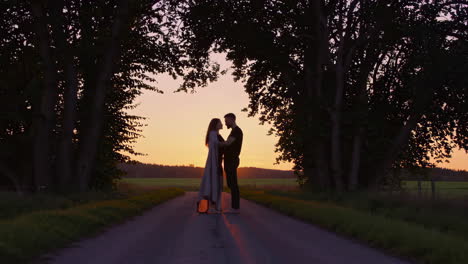 romantic silhouette of a couple embracing on a country road at sunset