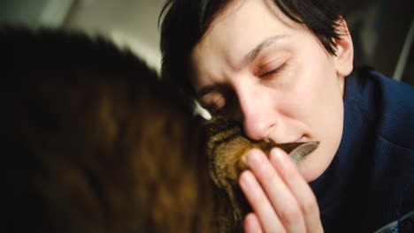 young woman is cuddling with her striped hosue cat