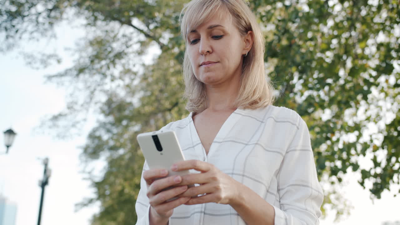 야외에서 스마트폰을 사용하는 여성