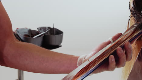 medium shot of hairdressing training head where hairdresser applies color paint with a paintbrush in a educational way close up of brush