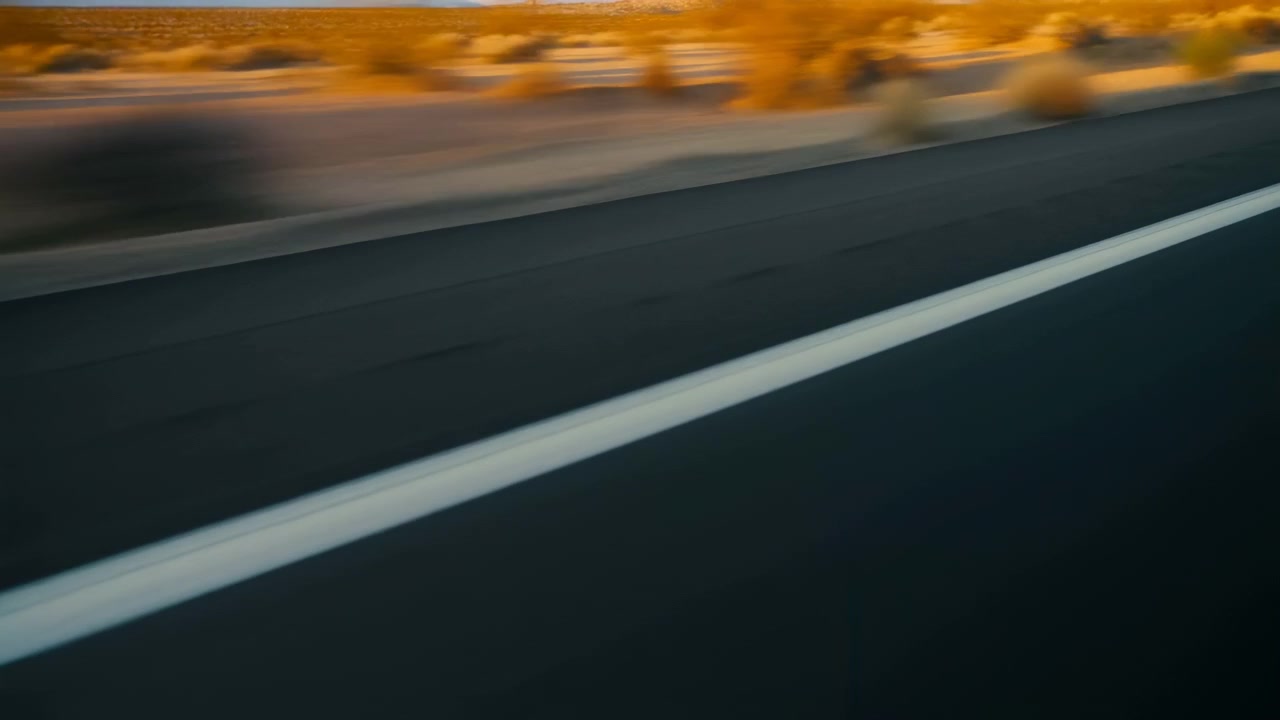 Una strada si snoda attraverso un paesaggio desertico, contrassegnata da linee bianche e asfalto, sotto una prospettiva dinamica e avventurosa in prima persona. I colori vivaci e lo sfondo pulito la rendono