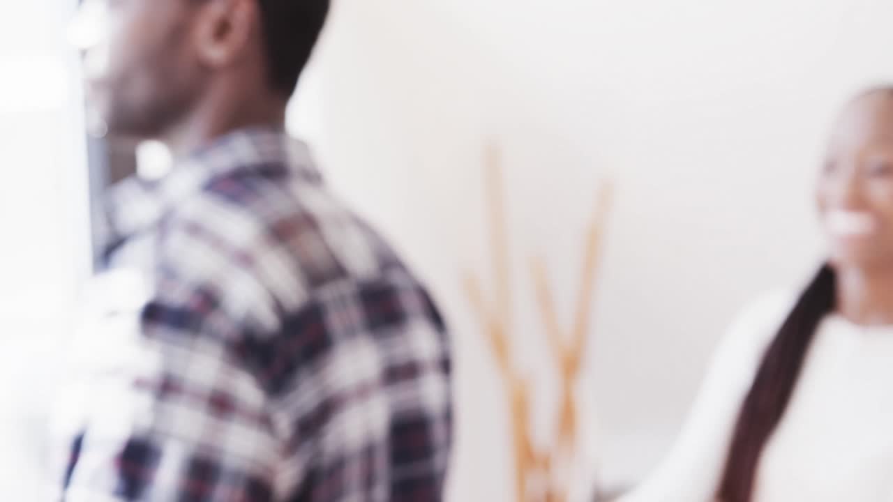 Happy african american couple smiling and embracing at home, in slow motion
