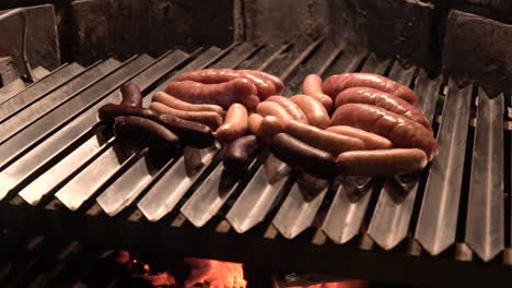 salchichas fritas en una parrilla de barbacoa de ladrillo por la noche