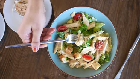 una mujer comiendo ensalada de césar.