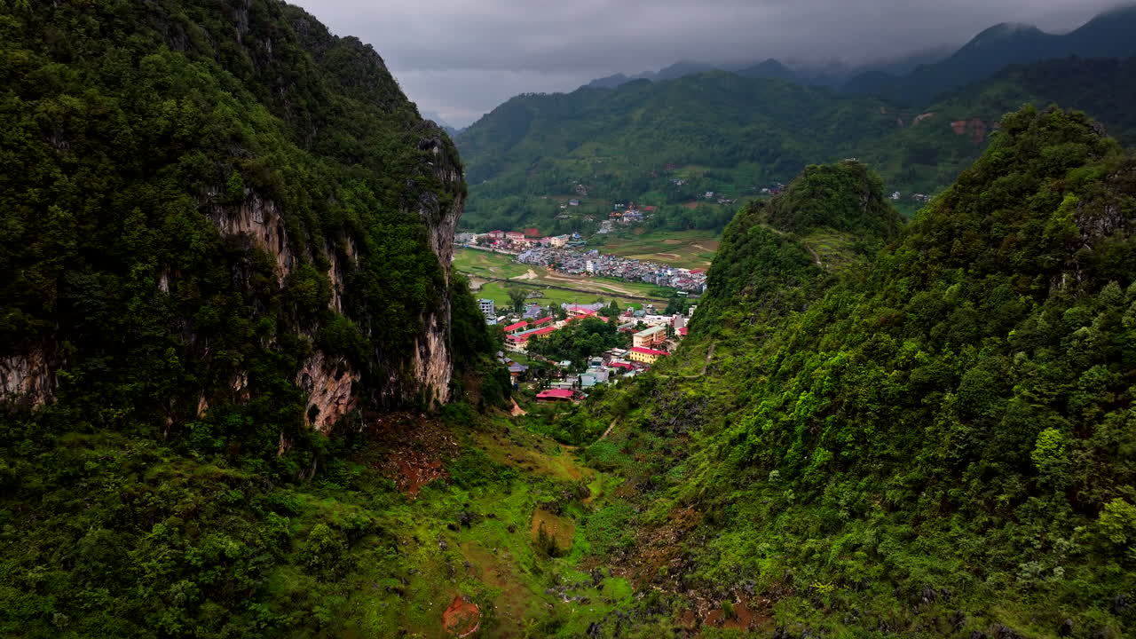 Stunning Aerial View of a Village Nestled in a Lush Green Valley Surrounded by Mountains
