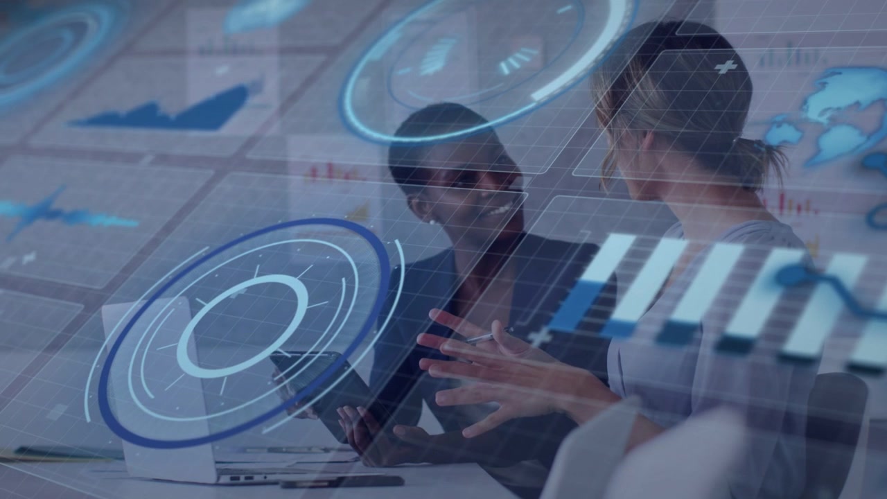 Two women reviewing tablet, right speaking gesturing, left tapping, blue HUD overlaying biz data
