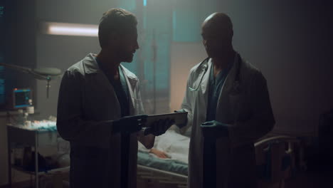 portrait two doctors meeting holding tablet computer in patient hospital room.