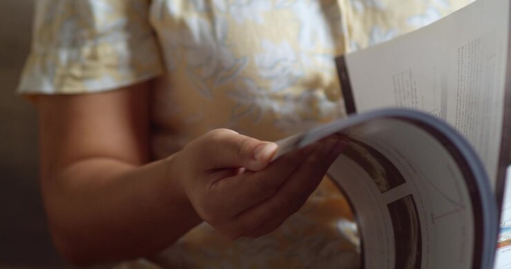 A detailed view of hands flipping through a magazine sparking design inspiration in a warm setting.