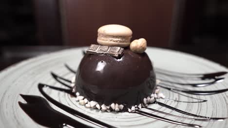 postre gourmet en un plato negro gira. poco macarrón con un pedazo de chocolate. comida giratoria. presentación del plato