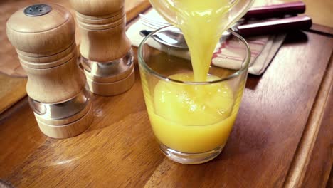 Orangensaft-In-Ein-Glas-Gießen,-Das-Morgendliche-Frühstück.-Zeitlupe-Mit-Rotierender-Kamerafahrt.