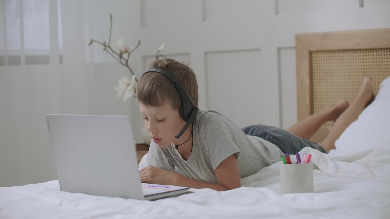 niño está usando una computadora portátil moderna con cámara web y auriculares inalámbricos para comunicarse con amigos que se quedan en casa