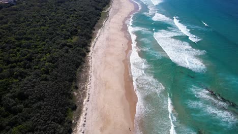 coolum beach with turquoise ocean and lush vegetation in queensland, australia - aerial drone shot