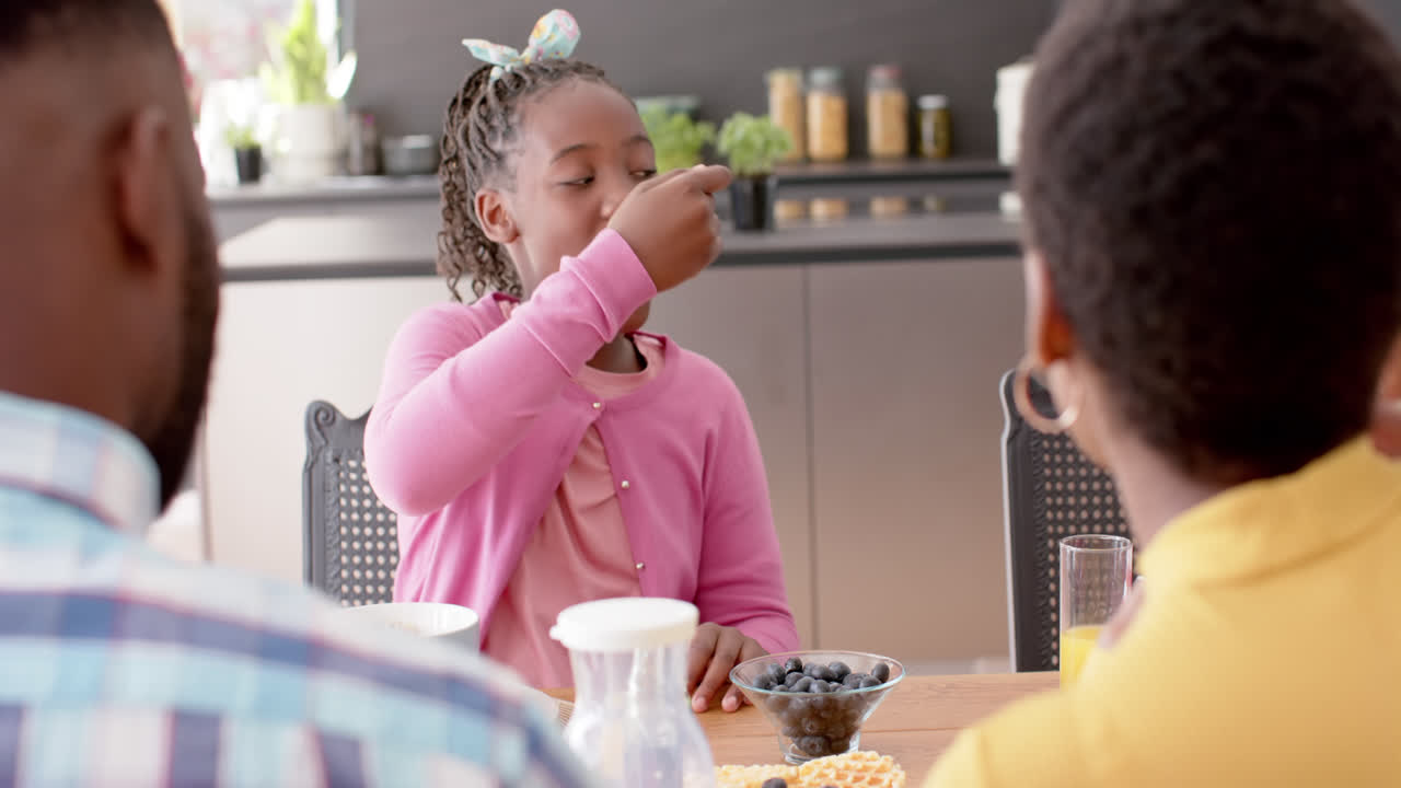African american parents, son and daughter eating in kitchen, slow motion