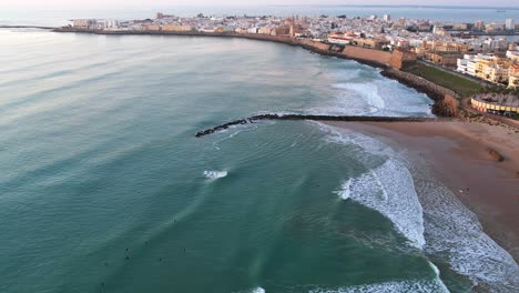 Surfers-in-the-water-waiting-for-the-wave-just-along-the-coastline-of-Cadiz,-Spain