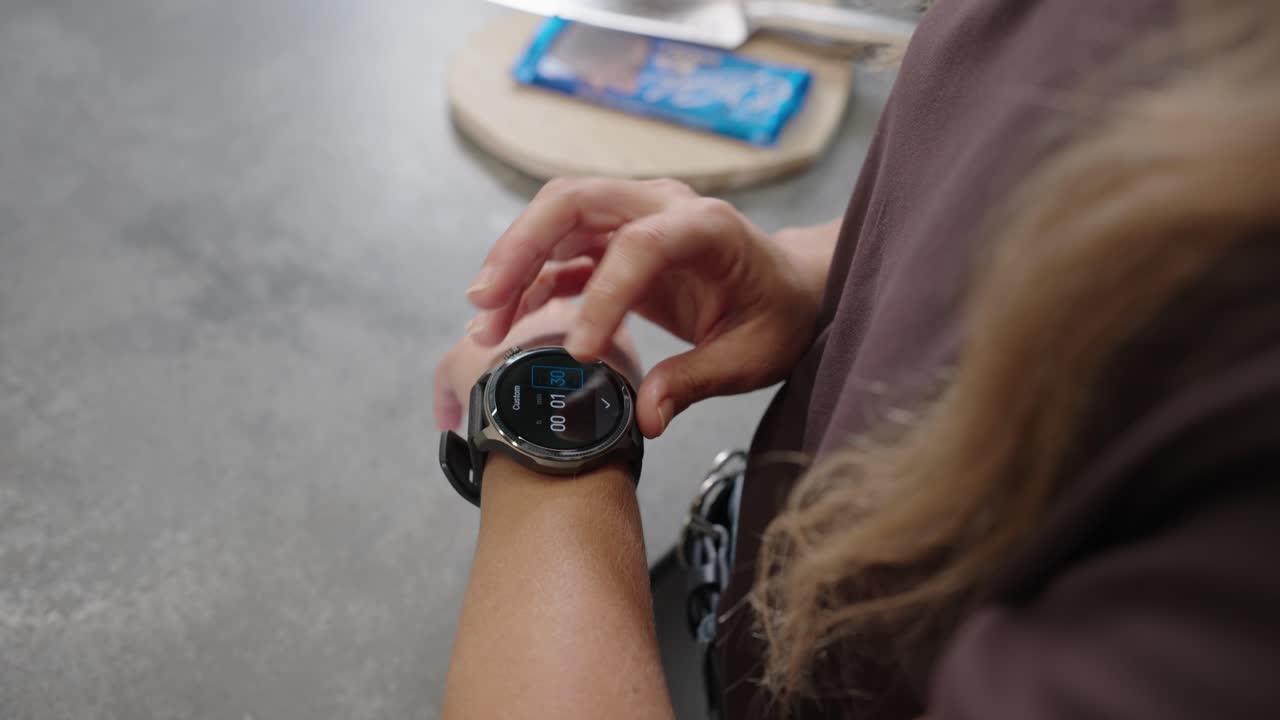 Close up of woman starting timer on smartwatch in kitchen