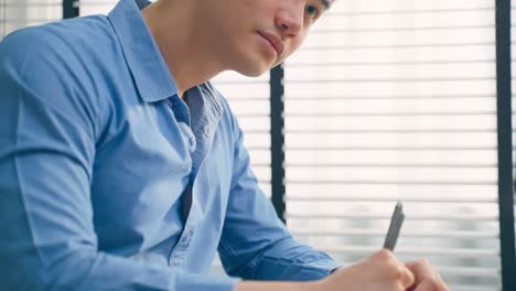 asian handsome business man using laptop computer working in office. attractive professional male employee worker sitting on table, feel happy and enjoy spending leisure time in corporate workplace.