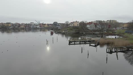 una vista escénica de pequeños puentes de madera sobre aguas tranquilas, un grupo de pájaros, un saunaraft y el hermoso paisaje urbano de karlskrona, suecia en el fondo-1