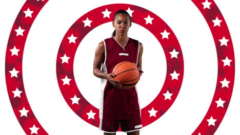 african american female basketball player holding a ball against stars on spinning circles