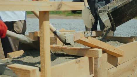 Making a socle in a private house. Workers pour concrete into the wooden formwork