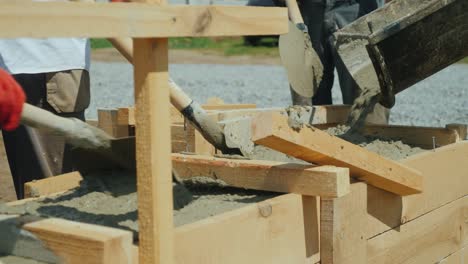 making a socle in a private house. workers pour concrete into the wooden formwork