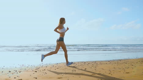 Una-Mujer-Joven-Con-Una-Figura-Esbelta-Se-Dedica-A-Gimnasia-En-El-Mar-Al-Amanecer.-Ella-Hace-Una-Carrera-A-Lo-Largo-De-La-Costa-Del-Mar.-Secuencia-De-Disparos-Con-Estabilizador-De-Cámara.-Cámara-Steadicam-En-Cámara-Lenta.