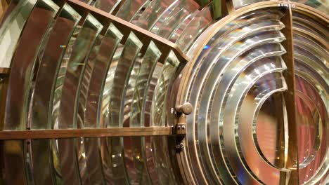 fresnel lens with brass structure, nautical lighthouse tower. detail of the glass lantern with rainbow spectrum. system of lamps and lenses to serve as a navigational aid. old sea searchlight beacon.