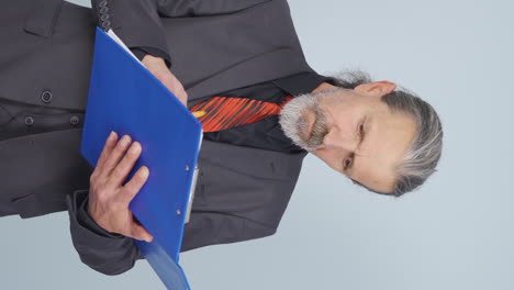 vídeo vertical de un viejo hombre de negocios examina el papeleo y se enoja.
