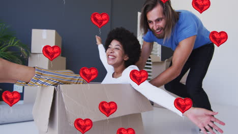 animación de iconos de corazón sobre una feliz pareja diversa que se muda a casa