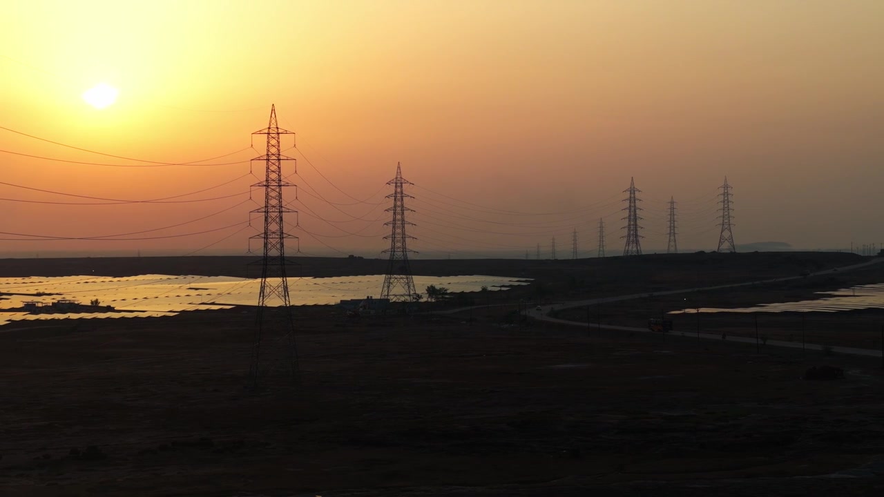 Drone panning left over a large photovoltaic solar farm with transmission towers, highlighting renewable electricity, power infrastructure and sustainable energy production.
