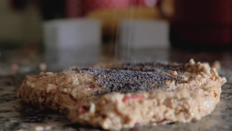 poppy seeds sprinkled on whole wheat flour and apple dough on the countertop