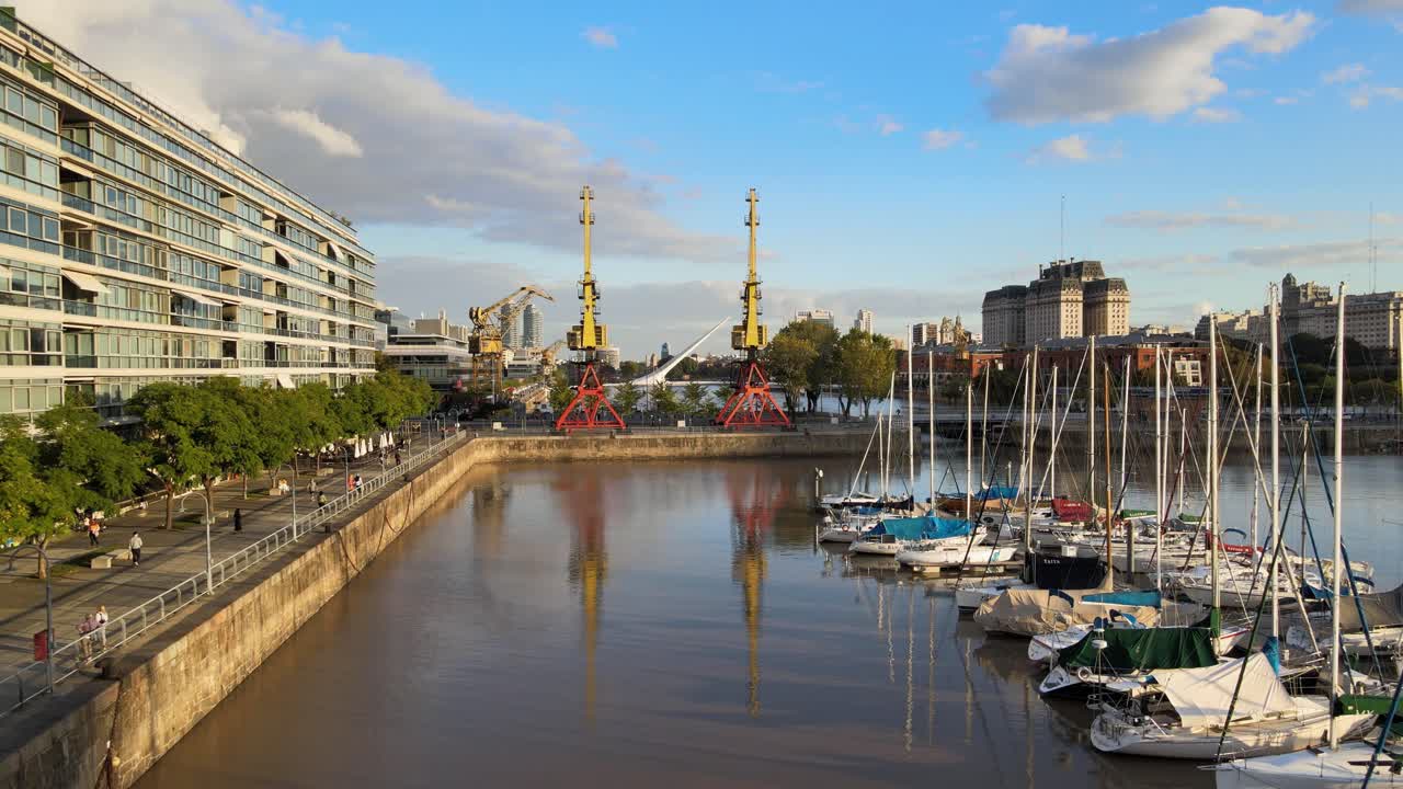 푸에르토 마데로 해안가의 부두 위로 날아가는 공중 돌리, 배경에 두 개의 오래된 항구 크레인