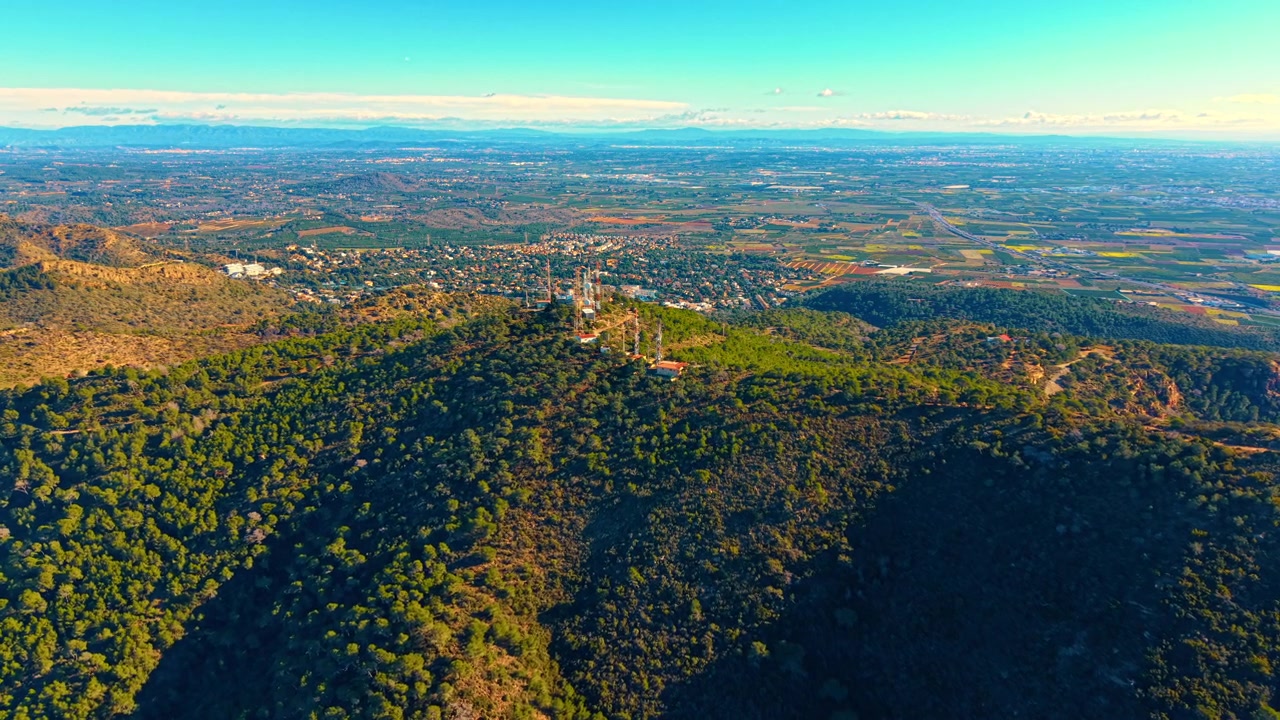 Vista chiara di colline e valle. La veduta aerea mostra colline verdi e una valle con una piccola città. Questa scena si svolge sotto la luce del sole in cieli azzurri limpidi.