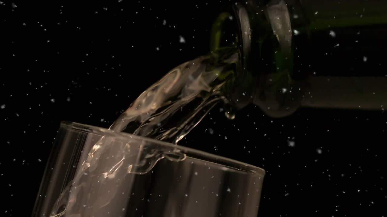Animazione di particelle bianche che cadono su champagne che si versa in un bicchiere su sfondo nero.
